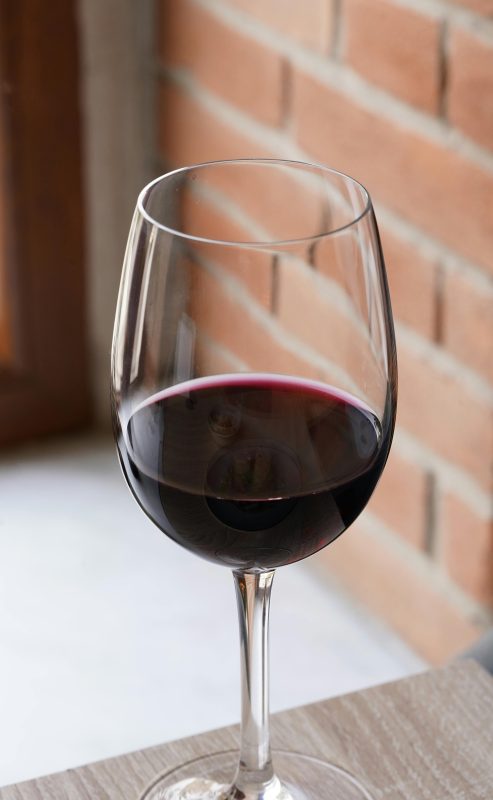Čaša crnog vina Babić uz zid od cigle – degustacija vina OPG Branko Marinov
